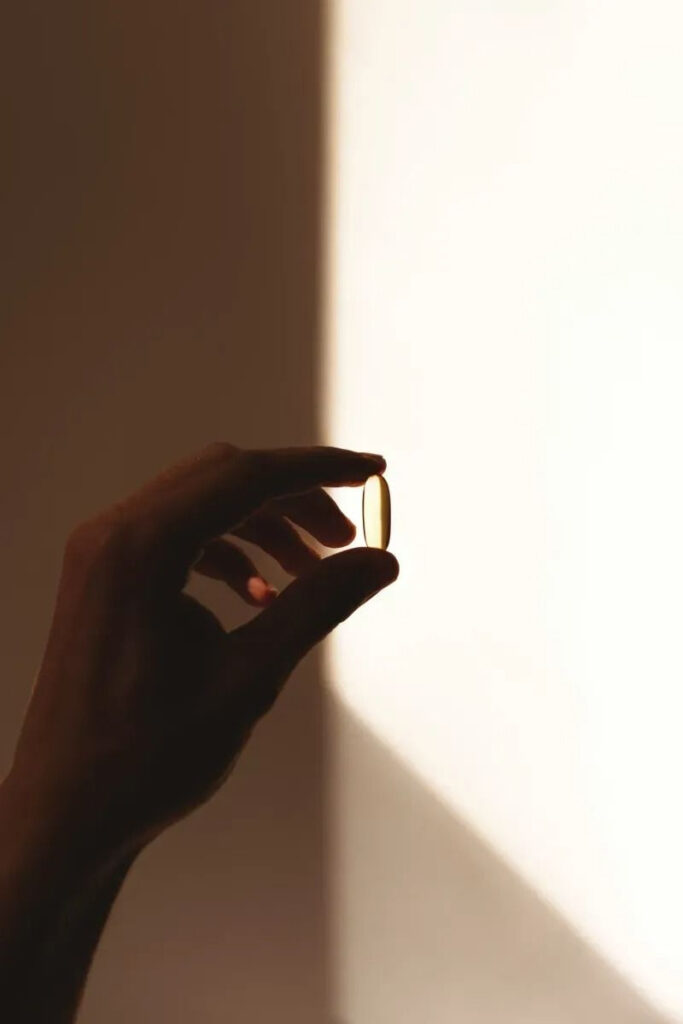 Qual é o melhor tipo de reposição hormonal? 2 Mão segurando uma cápsula de reposição hormonal oral, indicada em casos selecionados de terapia hormonal.