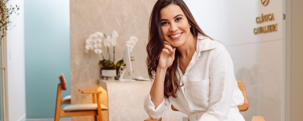 Dra. Laís Carvalho, ginecologista em Belo Horizonte, sentada no hall da Clínica Cavalieri em ambiente moderno e acolhedor.