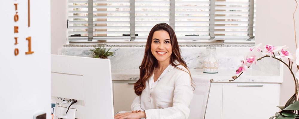 Dra. Laís Carvalho, ginecologista em Nova Lima, sentada em seu consultório acolhedor da Clínica Cavalieri.