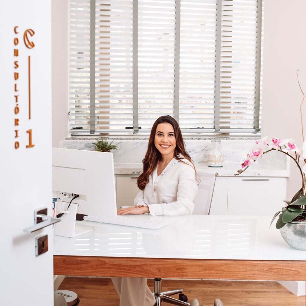 Dra. Laís Carvalho, ginecologista em Nova Lima, sentada em seu consultório acolhedor da Clínica Cavalieri.